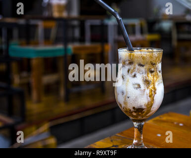 Eis kalten Glas weißer Joghurt mit Braun/Streifen sitzen auf einem Tisch mit verlorenen os Raum für Text und Hintergrund cafe Zimmer aus focuts. Stockfoto