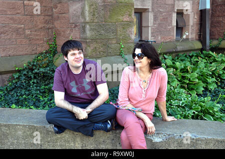 Frau und ein junger Mann sitzt an der Wand außerhalb von St. Paul's Episcopal Cathedral, Church Street, Buffalo, NY Stockfoto