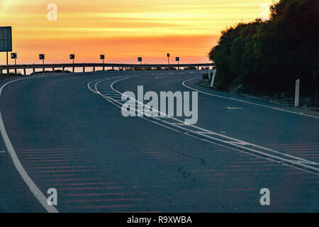 Curvy leere Straße entlang einer Felswand in Zypern mit Sonnenuntergang im Hintergrund. Stockfoto