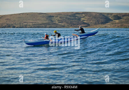 Vater und seinen zwei Söhnen zusammen Spass haben ein Kanu paddeln im Meer. Stockfoto