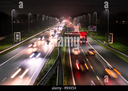 Berufsverkehr Schuß von oben über eine befahrene Straße zeigt Streifen Lichtspuren des unscharfen Autos an der A44 in der Nähe von Amsterdam - Den Haag. Stockfoto
