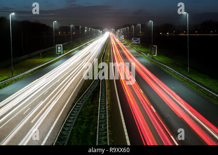 Berufsverkehr Schuß von oben über eine befahrene Straße zeigt Streifen Lichtspuren des unscharfen Autos an der A44 in der Nähe von Amsterdam - Den Haag. Stockfoto