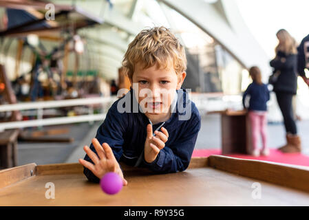 Kind konzentriert beim Spielen mit einem mittelalterlichen Ball Spiel. Stockfoto