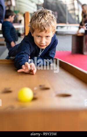 Kind konzentriert beim Spielen mit einem mittelalterlichen Ball Spiel. Stockfoto