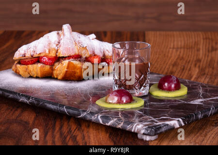 Croissant mit Schokolade und Sahne Erdbeere auf dem schwarzen Marmorplatte. Stockfoto