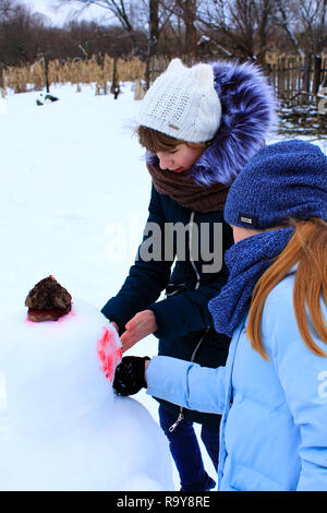 Zwei Mädchen machen Schneemann im Winter. Kinder Schneemann. Zwei Schwestern machen Schneemann im Winter Tag Stockfoto