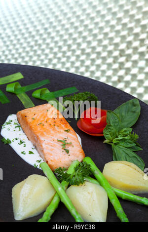 Lecker gebratenes Lachsfilet Gewürze auf Blau rustikal konkreten Hintergrund. Gekochte Lachssteak mit Kartoffeln Pfeffer Zitronensaft Knoblauch Olivenöl Löffel. Spac Stockfoto