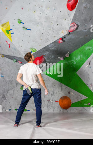 Kletterer Mann schob seine Hände in eine Tasche von Magnesia Pulver hinter seinem Rücken in der Boulder Halle Stockfoto