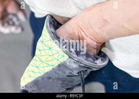 Kletterer Mann schob seine Hände in eine Tasche von Magnesia Pulver hinter seinem Rücken in der Boulder Halle Stockfoto