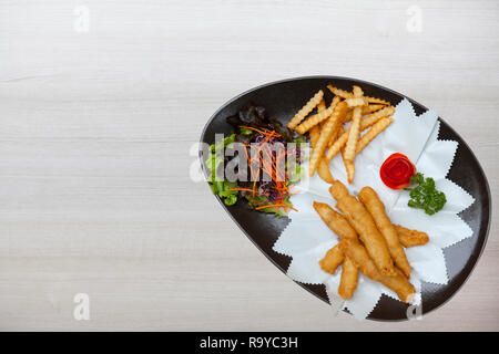 Gebratene Fischstäbchen mit Pommes Frites. Fischstäbchen. Fischstäbchen mit gebratenen Kartoffeln und Zitrone bereit zu essen, Holz- wand hintergrund, Holz Textur mit Natu Stockfoto