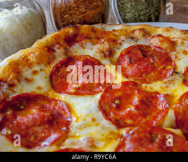 Teilweise Pepperoni Pizza mit drei Flaschen extras. chili Würzen, Oregano, Käse. Pepperoni ist schön rot Ton. Stockfoto