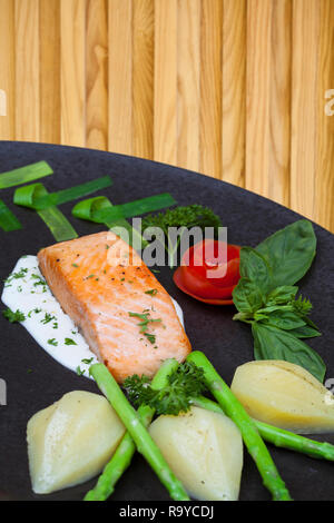 Lecker gebratenes Lachsfilet Gewürze auf Holzboden Hintergrund. Gekochte Lachssteak mit Kartoffeln Pfeffer Zitronensaft Knoblauch Olivenöl Löffel. Platz für Te Stockfoto