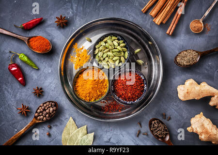 Verschiedene Gewürze wie Kardamom, Kurkuma, Chili, Bayberry, Lorbeerblatt, Paprika, Ingwer, Zimt, Kreuzkümmel, Sternanis und Nelke auf grunge Hintergrund Stockfoto