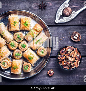 Türkisches baklava in der Nähe von Walnüssen und Nussknacker auf hölzernen Hintergrund Stockfoto