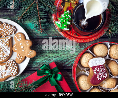 Weihnachtsplätzchen, Rot präsentieren und Tasse Kaffee mit Milch auf hölzernen grüner Hintergrund Stockfoto