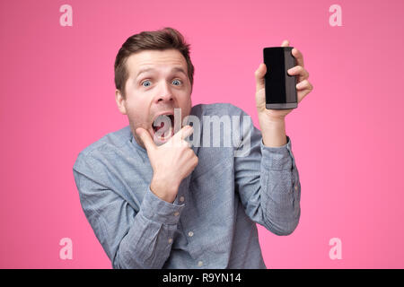 Hübscher junger Mann, Smartphone, Gadget, Kamera, über rosa Hintergrund isoliert.