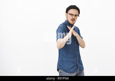 Kerl gerne zeigen einige Moves Kampfsportarten Lustige und gefühlvolle stilvolle junge Bartgeier männlich in Gläsern und schwarze Mütze, Palmen in asiatischen fighting Pose mit Karate über weiße Wand interessiert Stockfoto