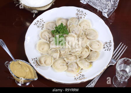 Russische Knödel mit saurer Sahne auf einem Holztisch Stockfoto