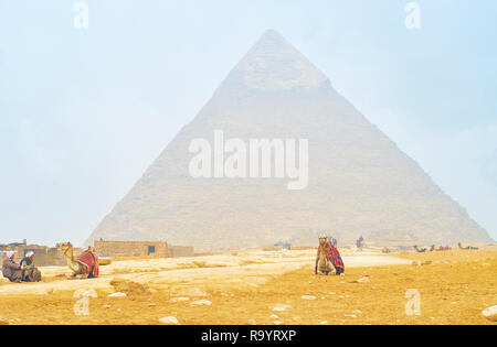 Gizeh, Ägypten - Dezember 20, 2017: Der alte Kameltreiber sitzen und für einen Kunden warten, um die archäologische Stätte und die Pyramiden von Gizeh zu Reiten, am Dezember Stockfoto