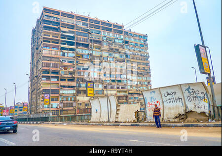 Kairo, Ägypten - Dezember 20, 2017: Die wohnlage in einem Vorort von Kairo mit schäbigen Hochhäuser Häuser und zerstörten Mauer entlang der Straße, auf Stockfoto