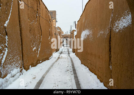 Ein leichter Schnee fallen, die eine hohe Mauern umgebene schmale Gasse Wand in Yazd, Iran. Stockfoto