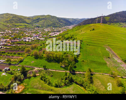 Luftaufnahme von Dorf und Wald im Frühling: kultivierte Land, Häuser und Wald von Flying drone. Stockfoto