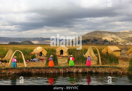 Frauen in traditionellen Festtracht willkommen Touristen schwimmenden Uros Inseln auf dem Titicacasee, Peru zu besuchen Stockfoto