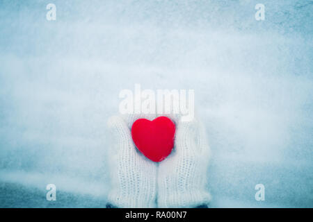 Rotes Herz in der Frau Hände tragen weiße wollene Handschuhe. Valentinstag Konzept Stockfoto