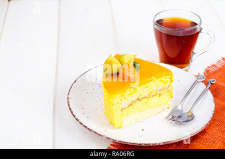 Stück mango Mousse Cake auf Platte, weiß Holztisch. Studio Foto Stockfoto