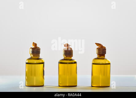 Drei kleine gelbe Flaschen voller Chemikalien auf hellen Hintergrund Stockfoto
