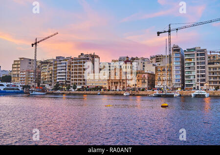 SLIEMA, MALTA - 18. JUNI 2018: Dämmerung über den Hafen mit Blick auf die Pfarrkirche von Jesus von Nazaret, den modernen Vierteln und malerischen Wolken spiegeln Stockfoto