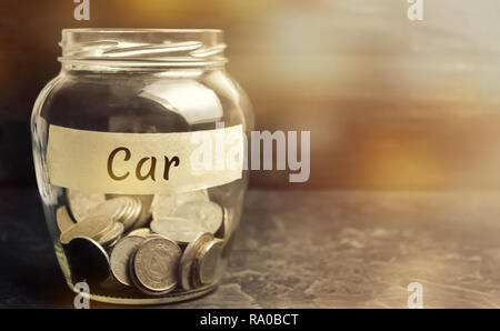 Glas Glas mit Münzen und die Inschrift 'Auto'. Das Konzept der Akkumulation von Geld für ein Auto. Geld sparen für ein Traum. Ein Auto zu kaufen. Familie Finanzierung Stockfoto