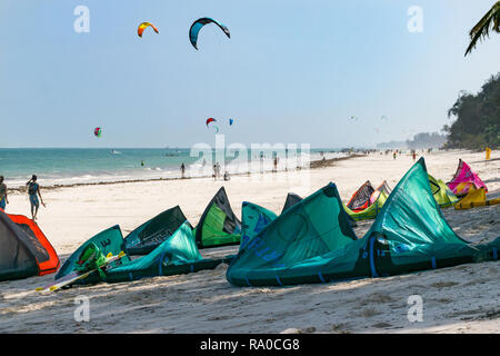 Mehrere kitesurfen Kites liegen auf dem weißen Sandstrand mit Kitesurfer im Hintergrund in den Indischen Ozean, Diani, Kenia Stockfoto