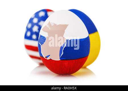 Schlag gegen die Orthodoxie: drei Ostereier in der Farbe der Flagge von Russland, der Ukraine und den USA gemalt, auf weißem Hintergrund Stockfoto