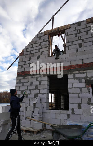 Ein Arbeiter mit einer Handwinde wirft eine Zementmörtel bin auf der zweiten Etage 2018 Stockfoto