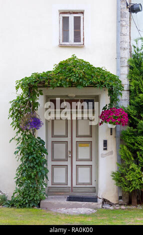 Vordere Tür der ein historisches Haus von Ivy umgeben und von Blumen dekoriert Stockfoto