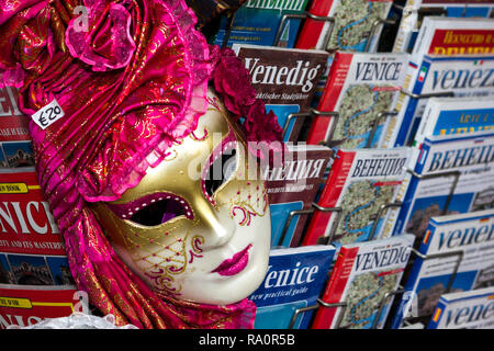 Venezianische Gesichtsmaske und mehrsprachige Reiseführer. Venedig Italien Stockfoto