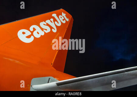 Eine Easyjet Höhenleitwerk auf der Landebahn in der Nacht mit einem stürmischen Himmel über Stockfoto