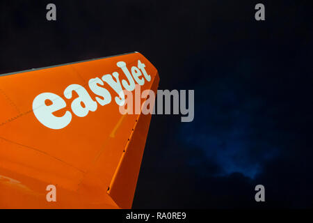 Eine Easyjet Höhenleitwerk auf der Landebahn in der Nacht mit einem stürmischen Himmel über Stockfoto