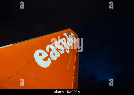 Eine Easyjet Höhenleitwerk auf der Landebahn in der Nacht mit einem stürmischen Himmel über Stockfoto