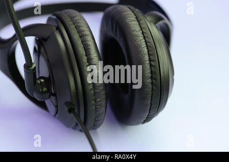 Schwarz Kopfhörer liegt auf einer bunten Pastell violett unterlegt. Musik Konzept Stockfoto