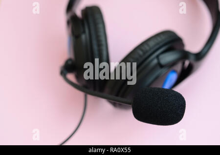Schwarz Kopfhörer liegt auf einem farbenfrohen Pastelltönen rosa Hintergrund. Musik Konzept Stockfoto