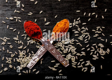 Gewürze in Löffel auf schwarzem Hintergrund Stockfoto