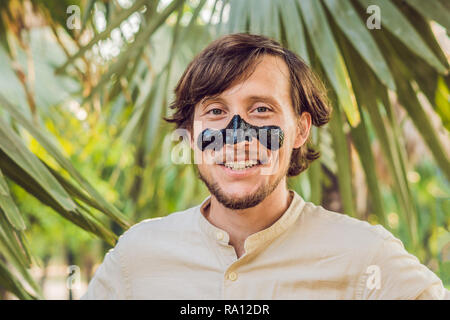 Glückliche Menschen mit schwarzer Maske auf dem Gesicht. Foto von Menschen empfangen von Wellnessanwendungen. Beauty Skin Care Concept Stockfoto