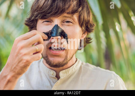 Glückliche Menschen mit schwarzer Maske auf dem Gesicht. Foto von Menschen empfangen von Wellnessanwendungen. Beauty Skin Care Concept Stockfoto