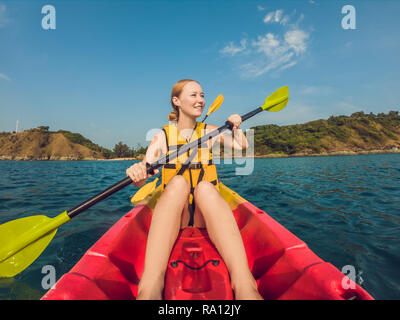 Lächelnden jungen Frau Kajakfahren auf dem Meer. Glückliche junge Frau Kanufahren im Meer an einem Sommertag Stockfoto