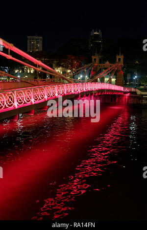 Die cavenaugh Brücke, die einzige Hängebrücke auf dem Singapore River, in Rot in der Nacht beleuchtet. Stockfoto