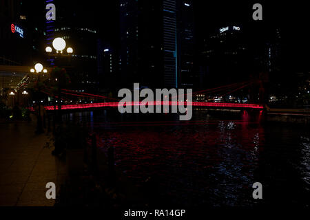 Die cavenaugh Brücke, die einzige Hängebrücke auf dem Singapore River, in Rot in der Nacht beleuchtet. Stockfoto