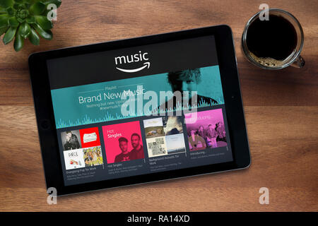 Die Amazon Musik App auf dem iPad Tablet gesehen, auf einer hölzernen Tisch zusammen mit einem Espresso und einem Haus Anlage (nur redaktionelle Nutzung). Stockfoto
