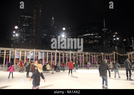 New York, USA. 27 Dez, 2018. Besucher laufen auf der Eisbahn mit Blick auf die Wolkenkratzer an der südlichen Spitze von Manhattan. Credit: Christina Horsten/dpa/Alamy leben Nachrichten Stockfoto